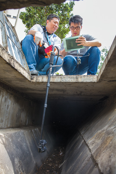 Mr Decry and colleague Azriel Lai use a handheld CCTV to check for blockages in drains.