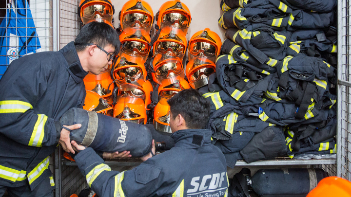 SCDF volunteer trainee firefighters handling firefighting appliances and equipment such as breathing apparatus cylinders or fire hoses and nozzles