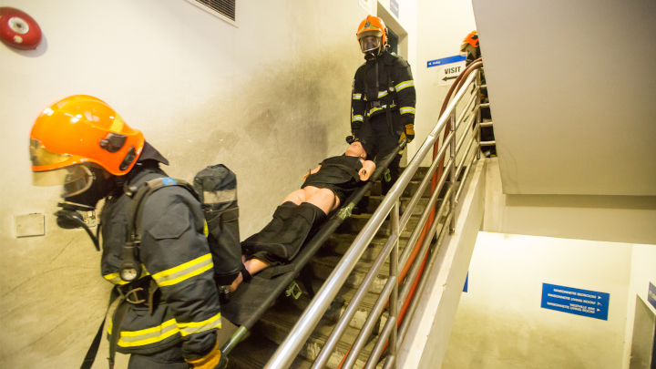 Trainee SCDF volunteer firefighters transporting a 75kg manikin safely down the narrow stairwell 