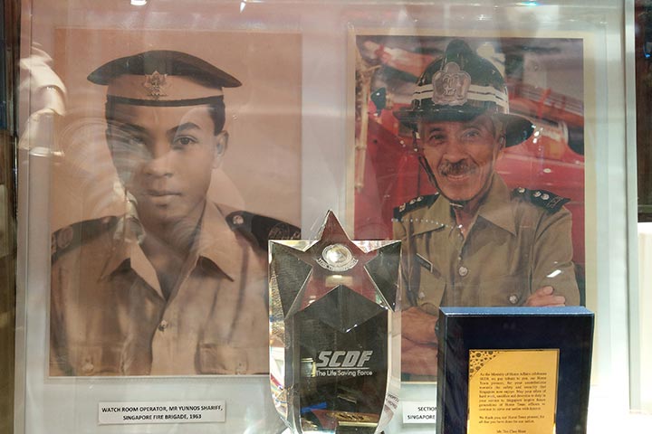An old photo of WO(V) Yunnos as a Singapore Fire Brigade watch room operator in 1963 stands next to a more recent photo of him at the Civil Defence Heritage Gallery.
